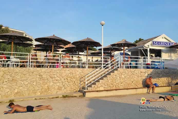 Betonirana plaža sa kamenim stepenicama koje vode do caffe bara sa suncobranima