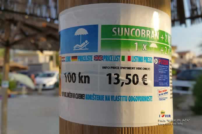 Natpis o koštanju najma suncobrana u eurima naljepljen na stup od bambusa