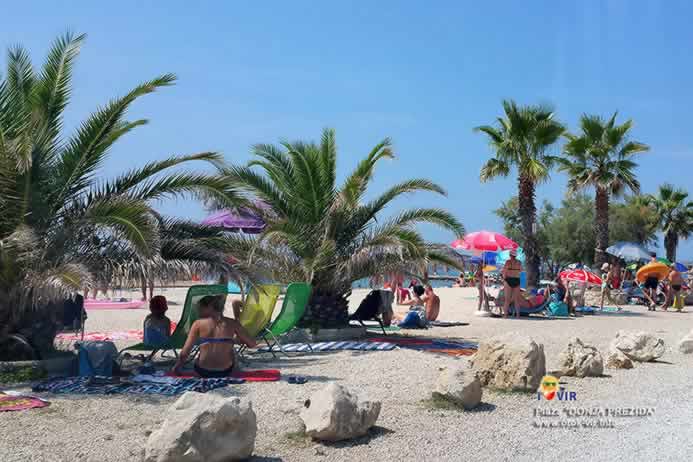 Turisti pod palmama na šljunčanoj plaži u Prezidi