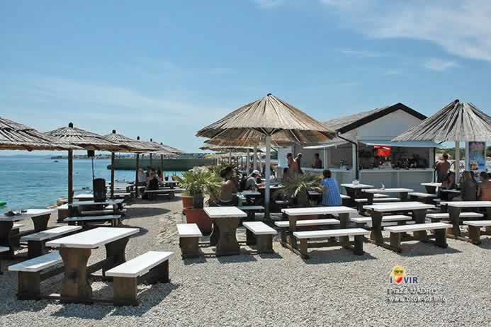 Beach bar sa stolovima i drvenim klupama na plaži Jadro