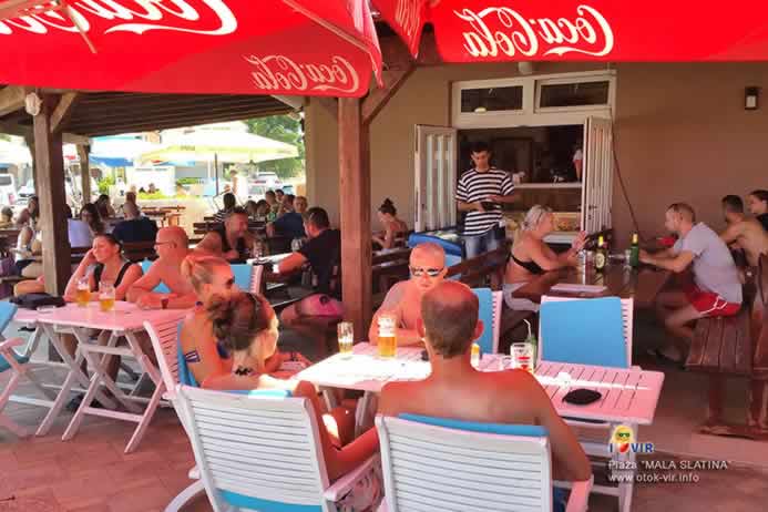 Gosti u kafiću na ljetnoj terasi ispod suncobrana uživaju u hrani i piću