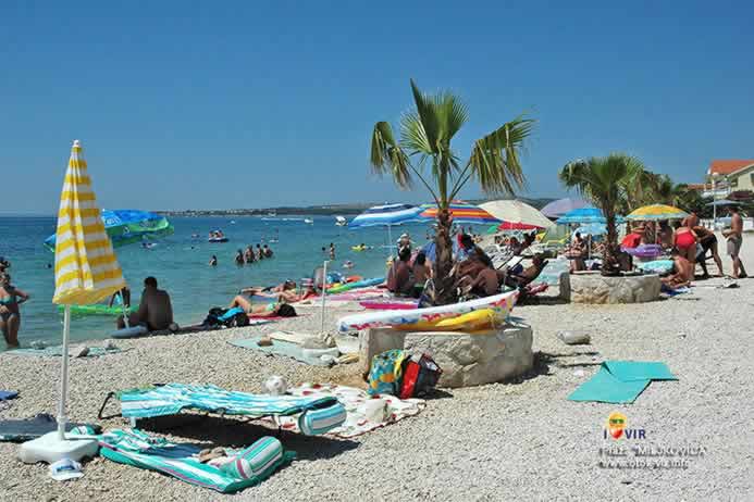 Turisti na plastičnim ležaljkama pod suncobranima na plaži Miljkovica