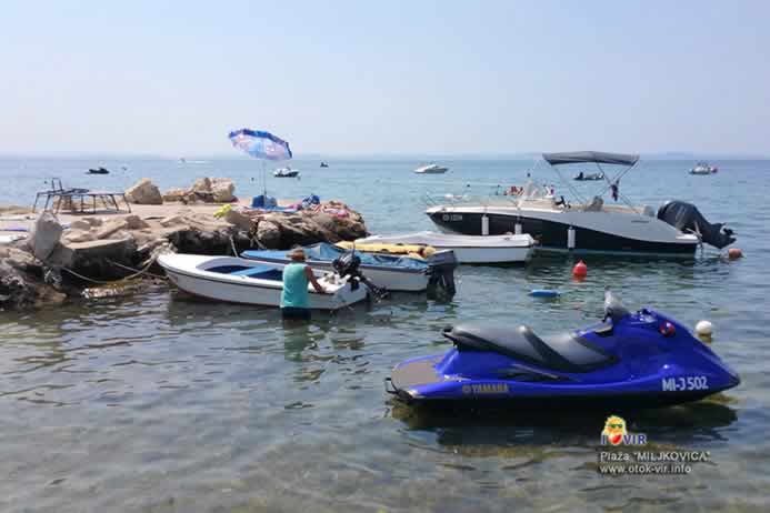 Plavi vodeni skuter pored bijelog čamca i glisera s natkrovom pored mola uz more