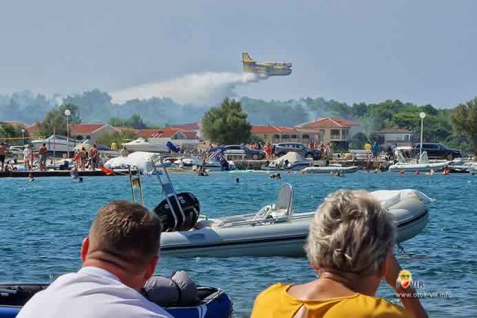 Turisti promatraju gašenje požara kanadera u blizini plaže po danu