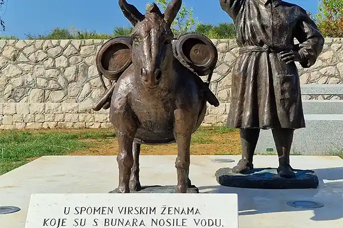 Natpis i spomenik žene sa burilom i magarcom