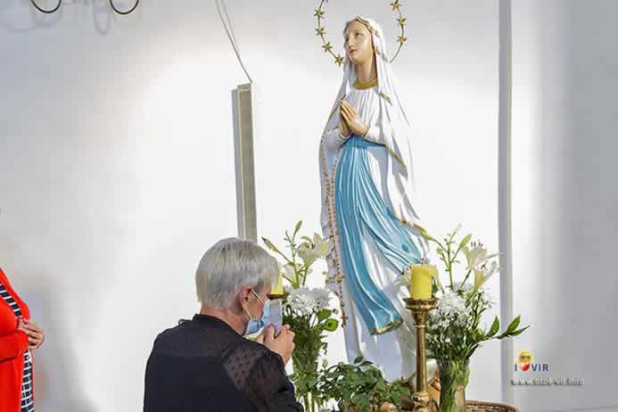 Molitva starice ispred kipa Majke Božje u crkvi